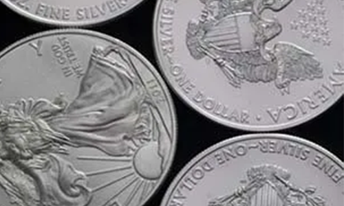 Several American Silver Eagle coins are displayed against a dark background. Four coins are partially visible, showcasing intricate designs and inscriptions.