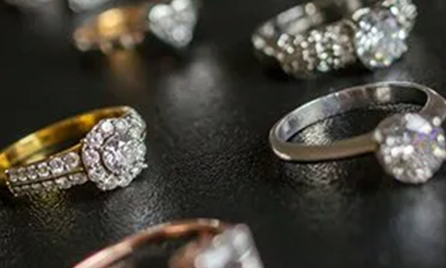 Close-up shot of various diamond rings displayed on a black surface.